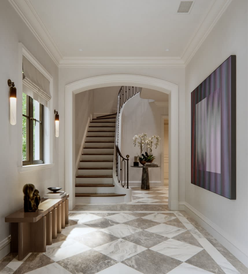 Grand entry foyer at The George with checkered marble floors, a sweeping staircase, and soft natural light from an overhead skylight
