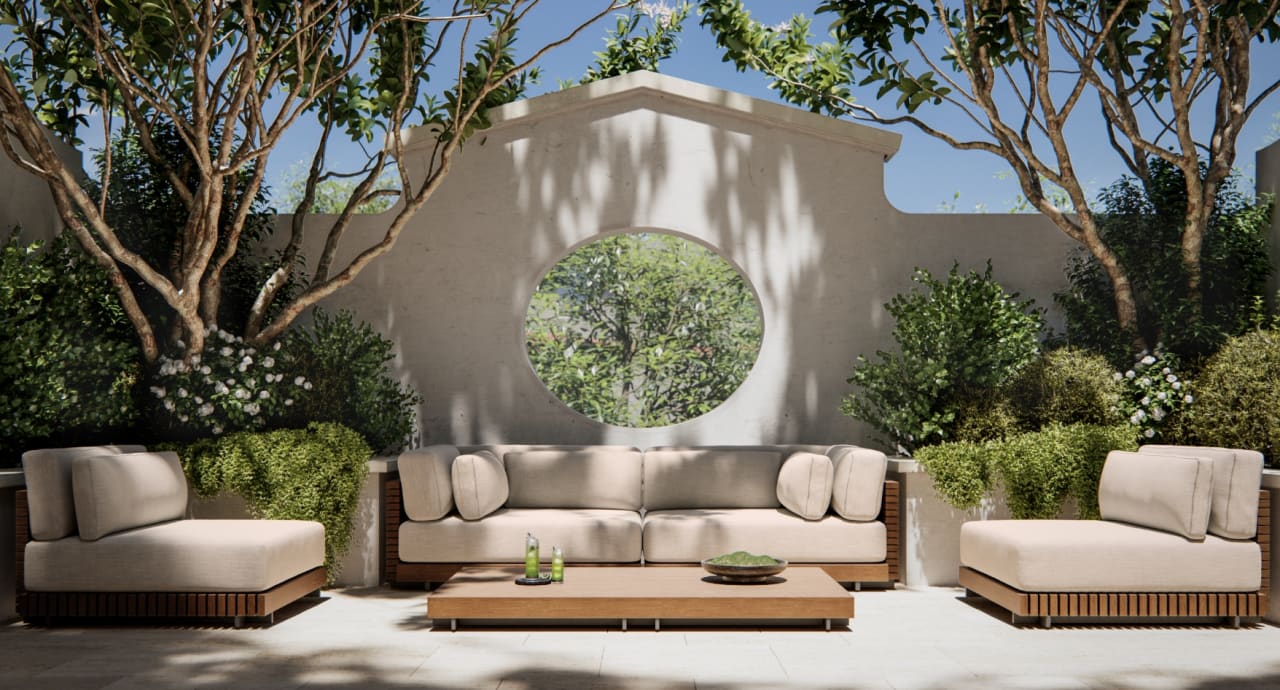 Shaded terrace at The George with a carved stone circle-motif garden wall, layered greenery, and soft sectional seating arranged for relaxed entertaining