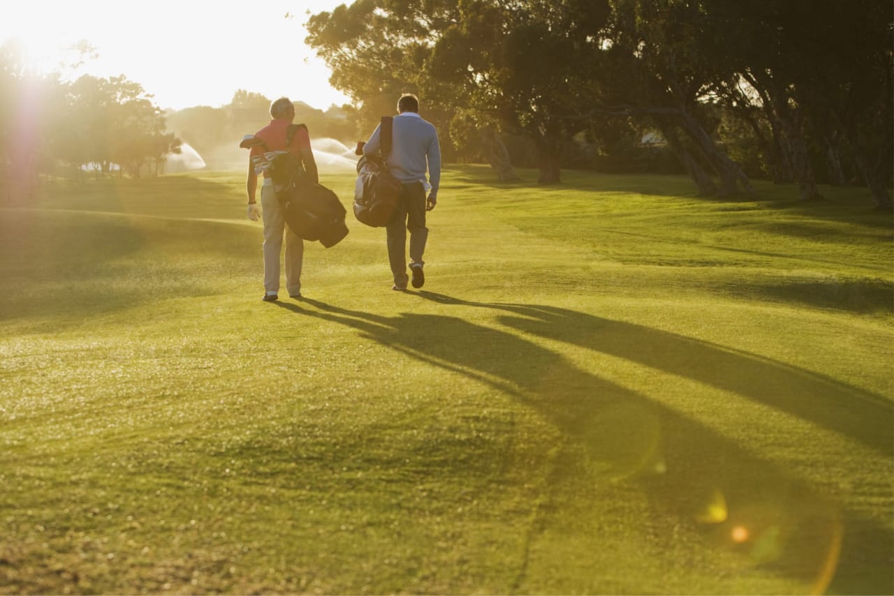Two men walking together at a sun-lit golf club