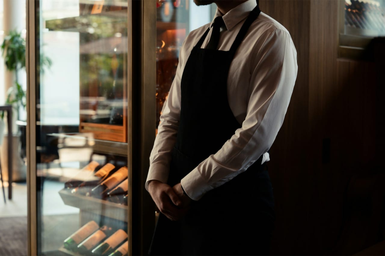 White-gloved hands of a formal server adjusting a jacket cuff, evoking the refined hospitality of Coral Gables dining