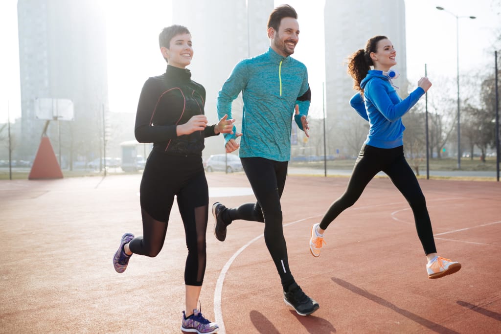 Happy friends exercising by running together outdoors living active healthy lifestyle