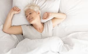 Senior woman lying down in her bed at home