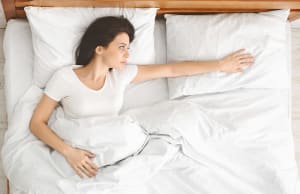 Depressed young woman lying in bed and feeling lost