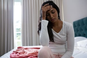 Tired woman sitting on bed