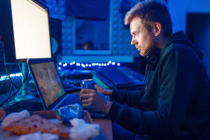 Gamer playing video games late and drinking an energy drink with caffeine