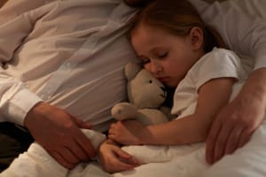 child with nightmares sleeping in her father arms