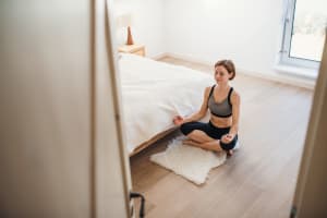 A young woman doing yoga exercise in morning in a bedroom