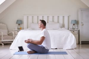 Man Meditating in front of bed