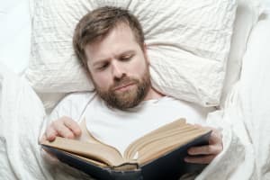 man reading a book in bed