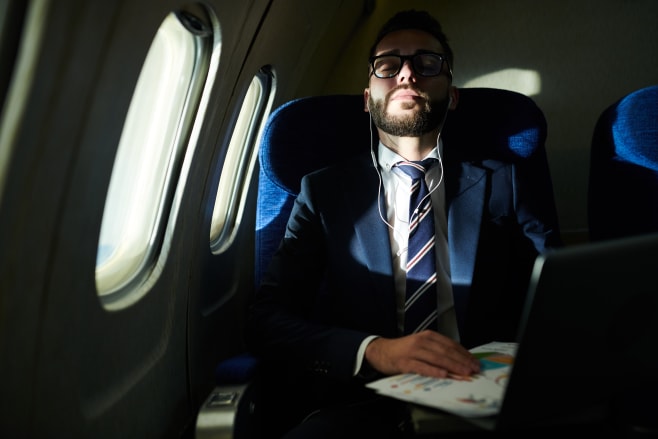 Portrait of successful businessman sleeping during long flight in dimly lit plane