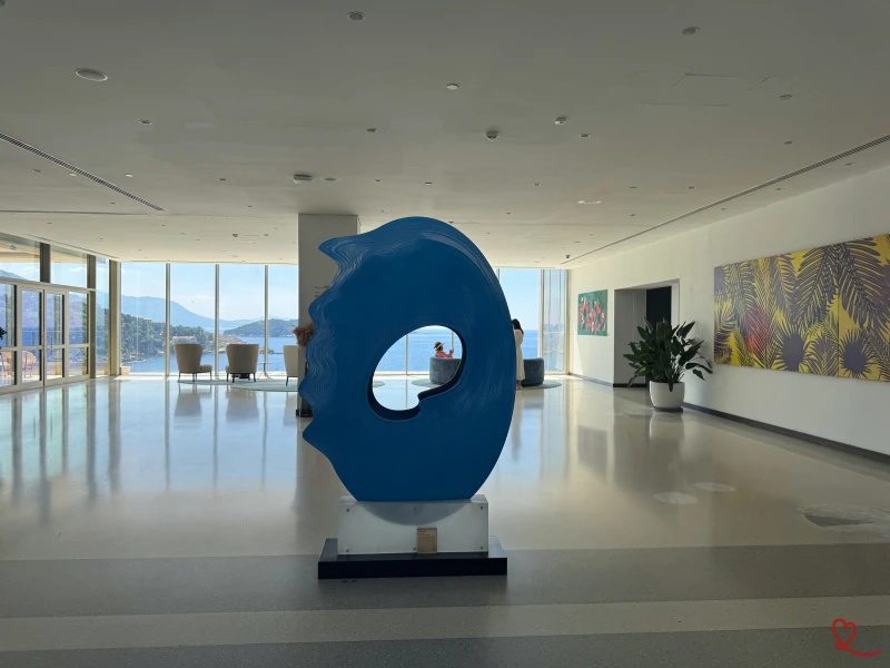 Escultura de olas azules en un luminoso salón con vistas al mar.