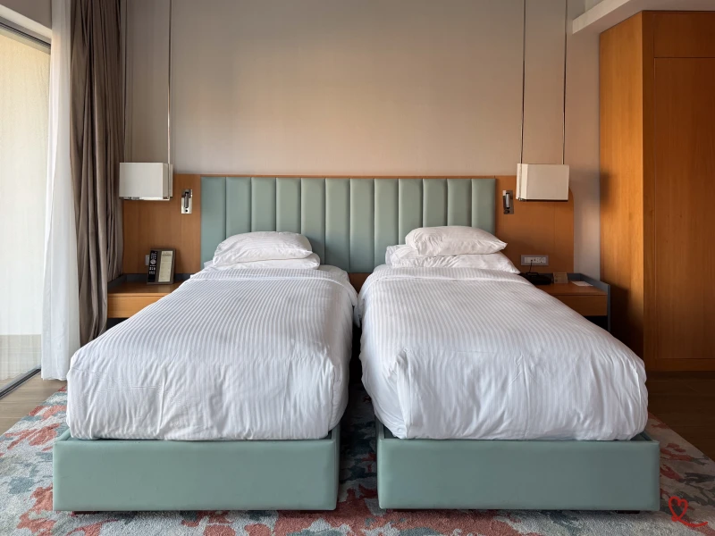 Habitación de hotel con dos camas individuales y decoración moderna.