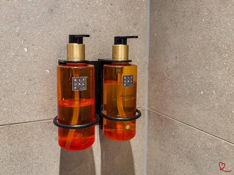 Deux flacons de shampooing et de gel douche orange fixés au mur.