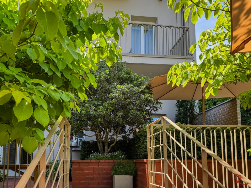 Escalier menant à un jardin avec des arbres et un parasol.