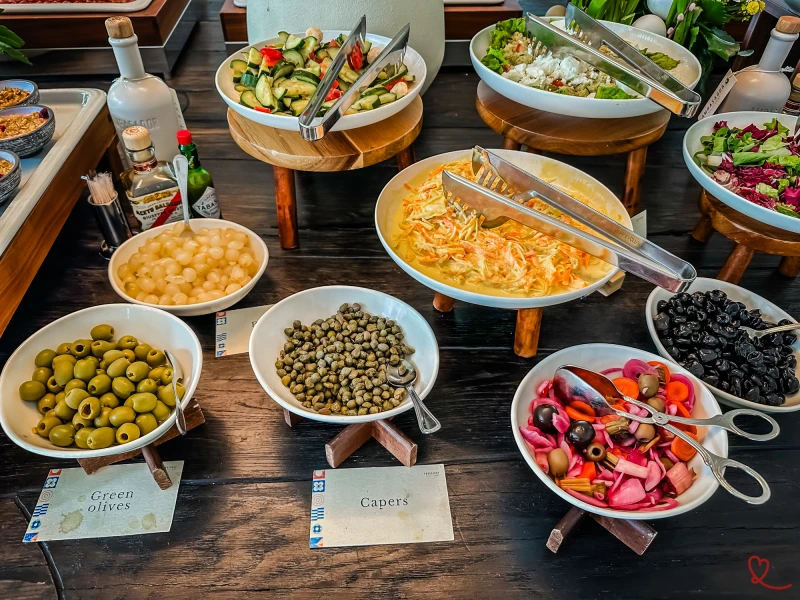 Saladas variadas e guarnições em taças sobre uma mesa.