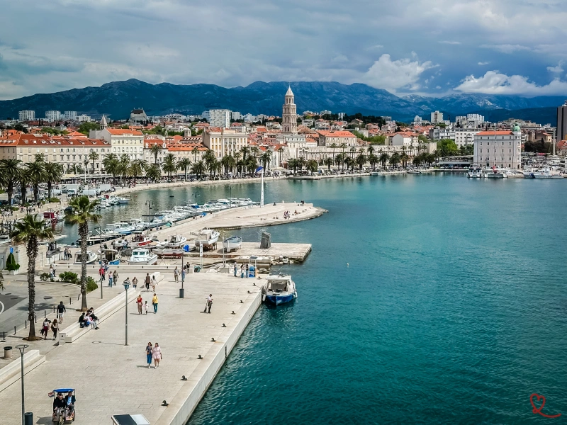 Vista panorâmica do porto de Split com barcos e montanhas ao fundo.