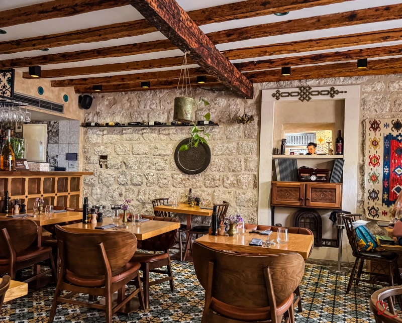 Interiør i en restaurant med træborde og en disk af sten.