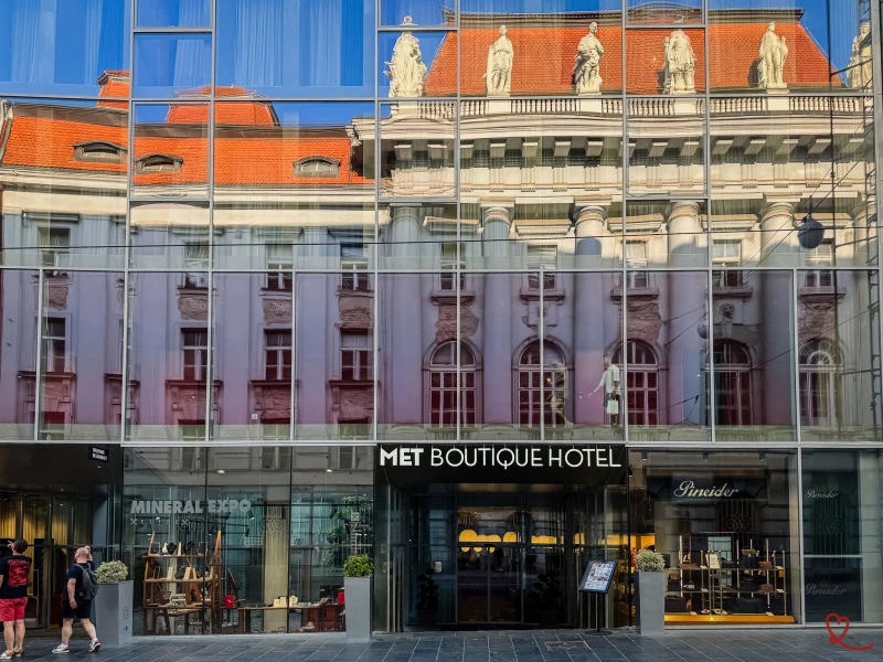 Façade du MET Boutique Hotel avec reflets d'un bâtiment historique.