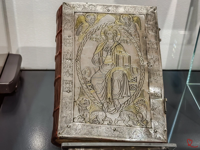Libro antico con copertina in argento raffigurante Cristo circondato da angeli e leoni.