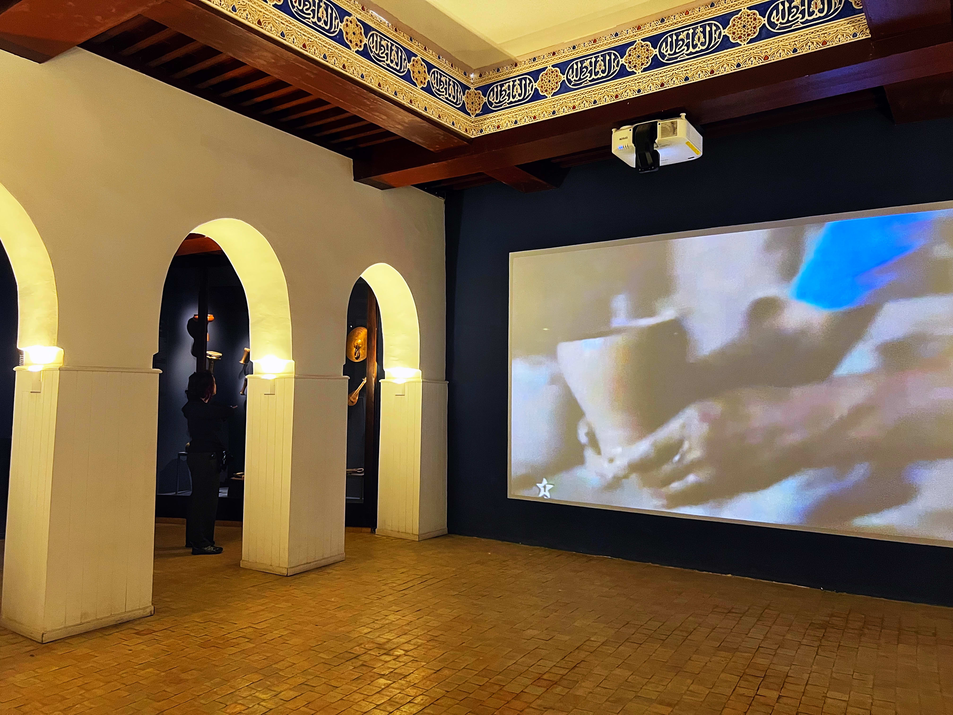 Salle d'exposition avec arches et projection vidéo au Musée Dar Jamaï
