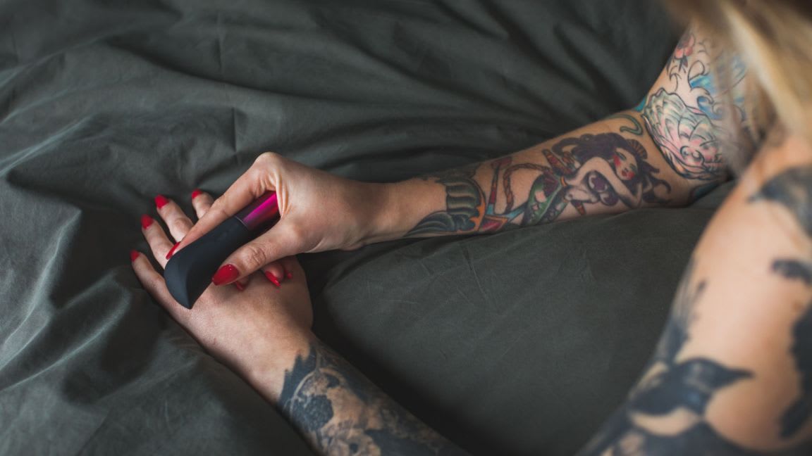 Tattooed arms holding Amo in bed