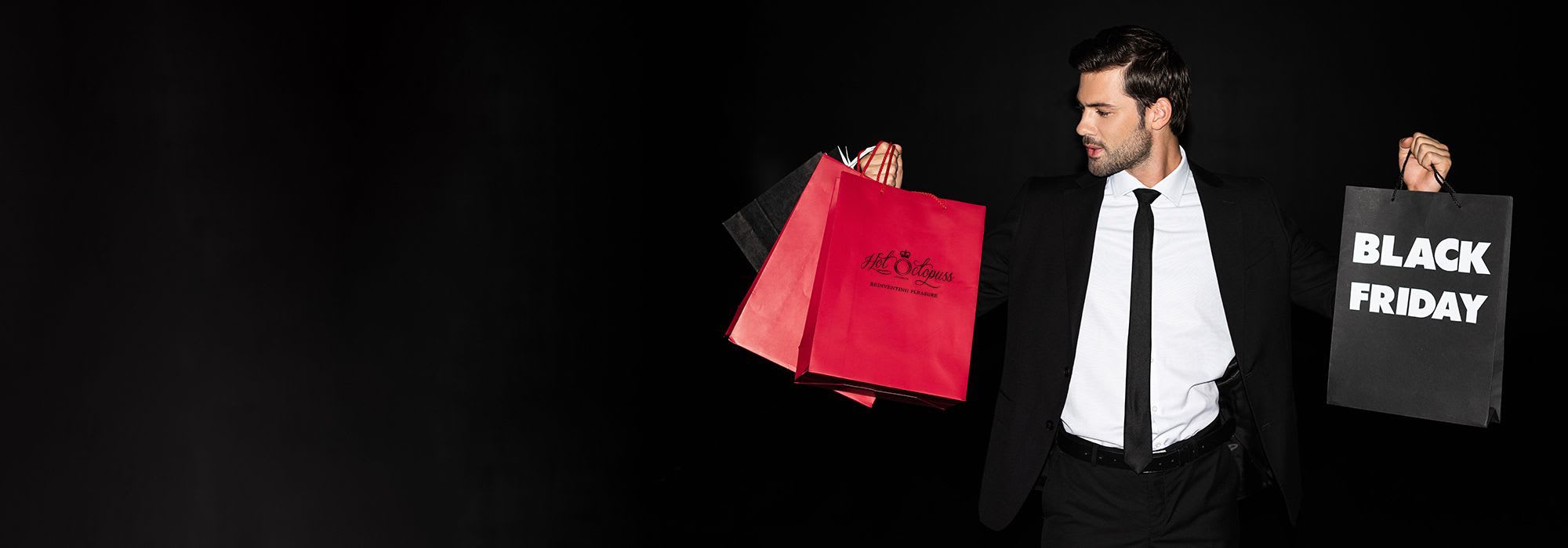 Man in a suit holding shopping bags in his hand, one reads black friday