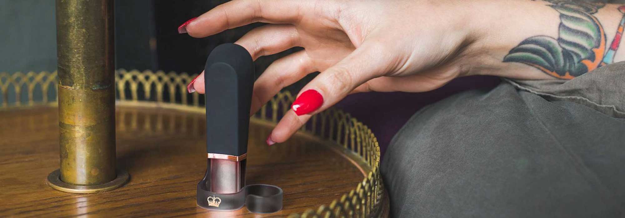 hand with painted red nails reaching for the digit on a gold ridged bedside table