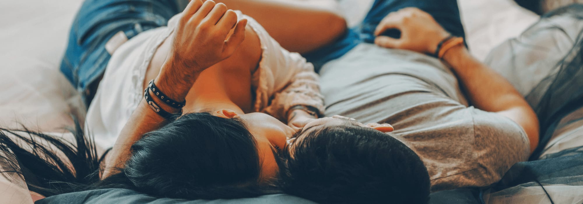 a couple kissing while laying on a bed