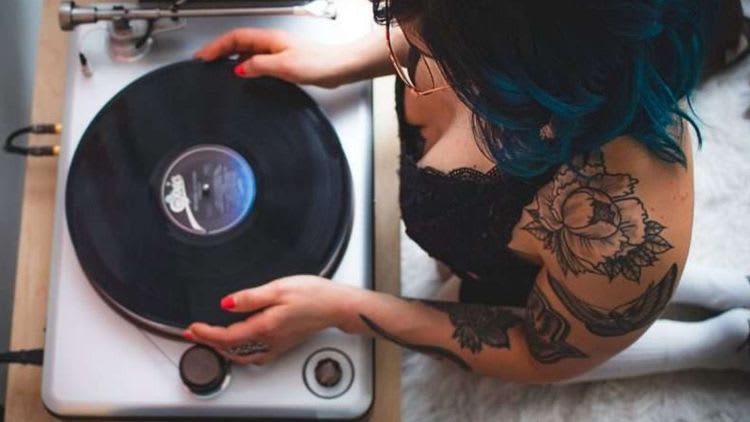 tattoo woman with blue hair putting a record on