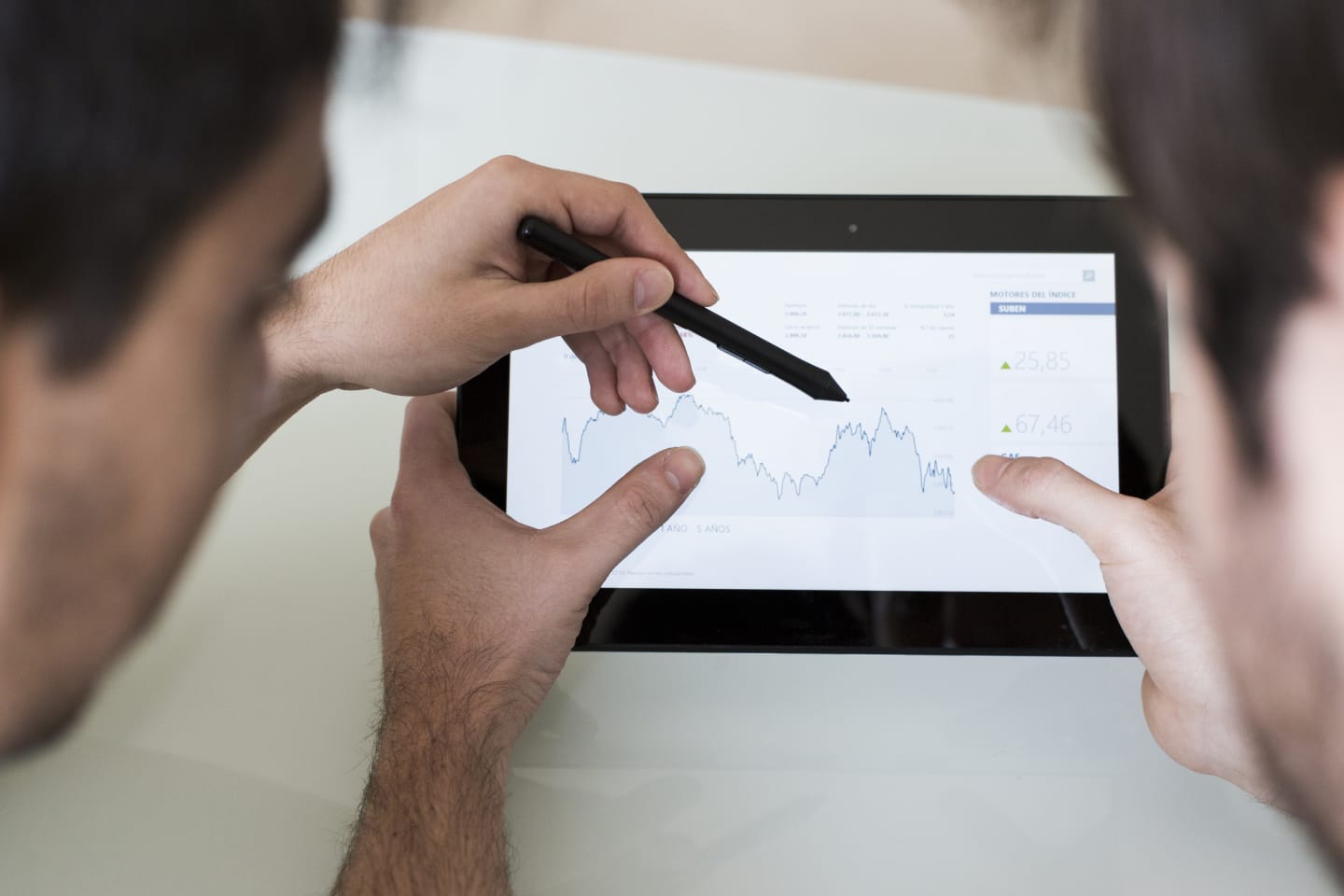 Due colleghi osservano l'andamento di un grafico su un tablet, uno indica un punto con la penna