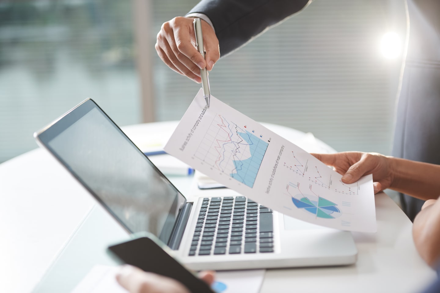 Analisi di grafici e report stampati accanto a un laptop durante una riunione di lavoro
