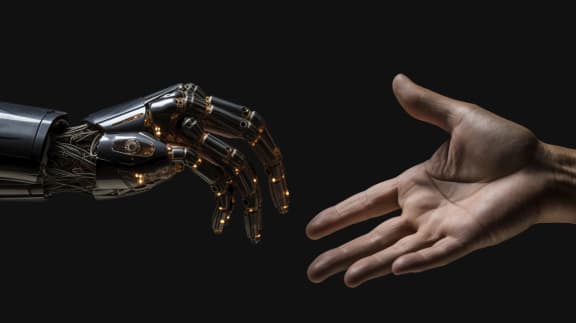 Una mano robotica e una mano umana si avvicinano l'una all'altra su sfondo scuro