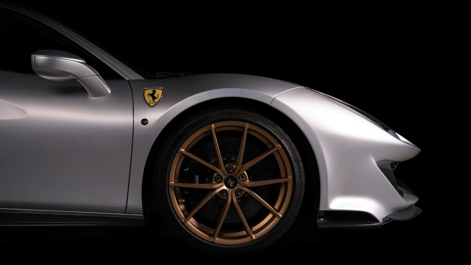 Fiancata anteriore di una Ferrari argento con cerchi color bronzo e lo scudetto del Cavallino, fotografata su fondo nero per New Bassani Auto