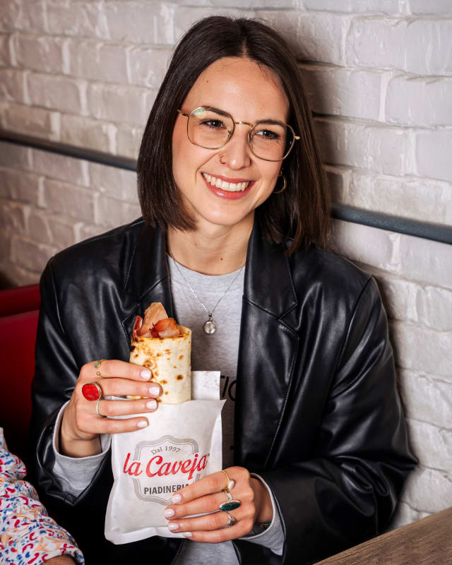 Donna con giacca di pelle che tiene una piadina La Caveja