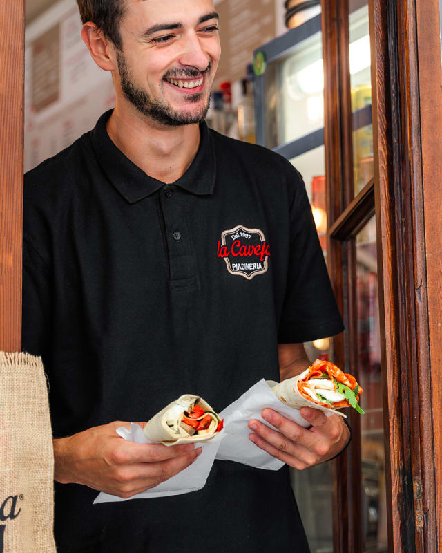 Ragazzo con polo La Caveja tiene una piadina davanti alla piadineria