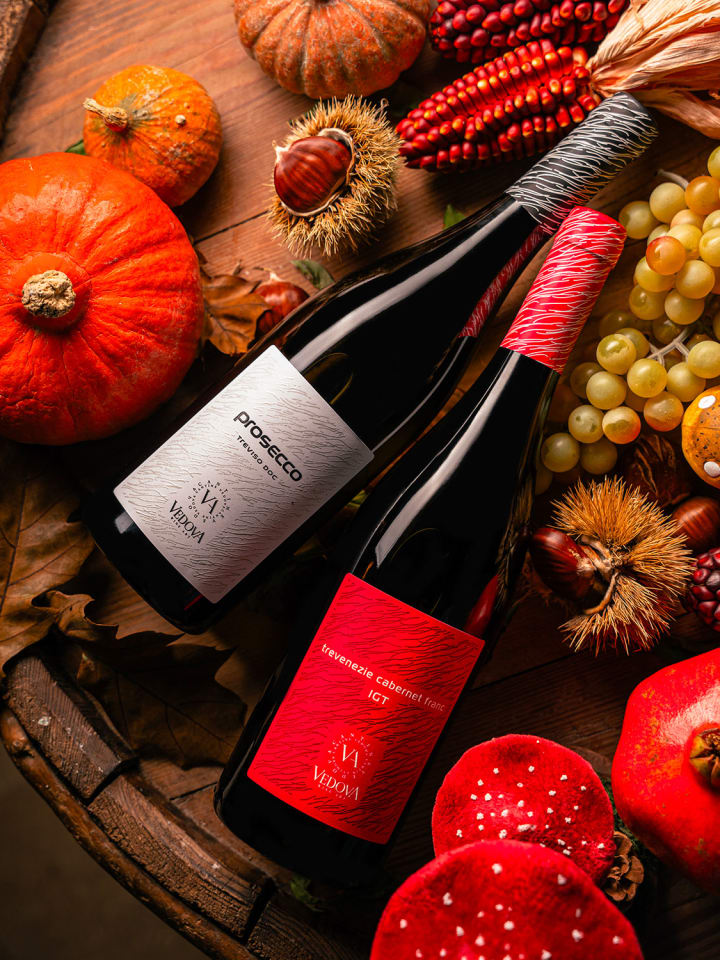 Prosecco Treviso DOC e Cabernet Franc IGT Vedova adagiati su una botte, tra zucche, castagne, uva e melograni autunnali