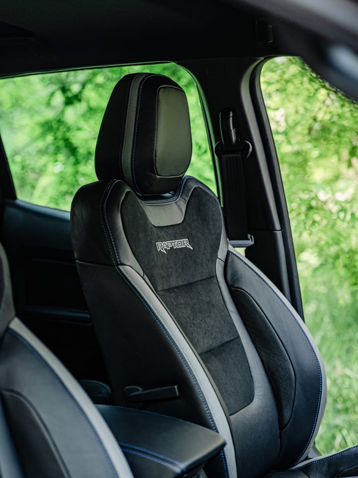 Sedile anteriore in pelle e alcantara con la scritta Raptor, visto dalla portiera aperta di un Ford Ranger con il bosco sullo sfondo