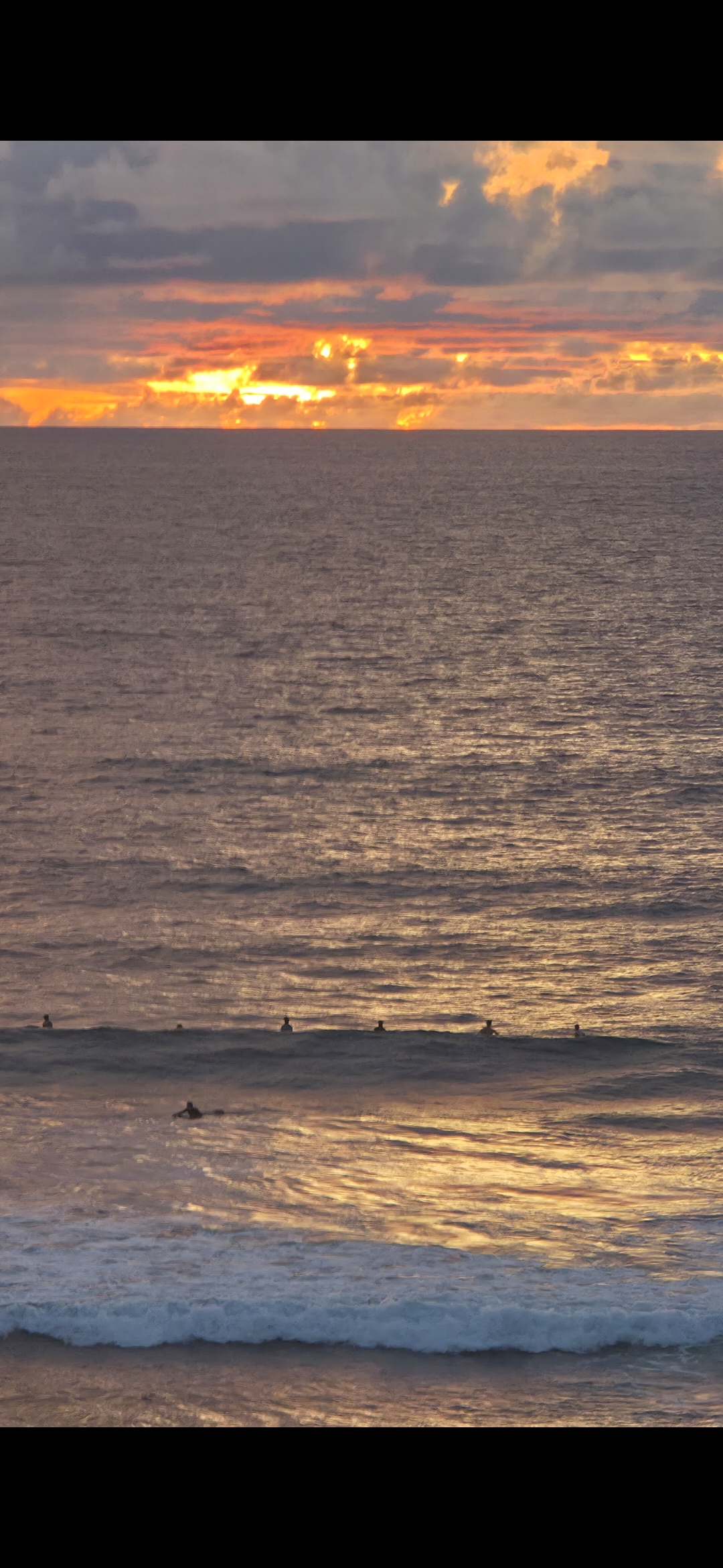 Surfers at sunset Padang Padang Beach Uluwatu Bali