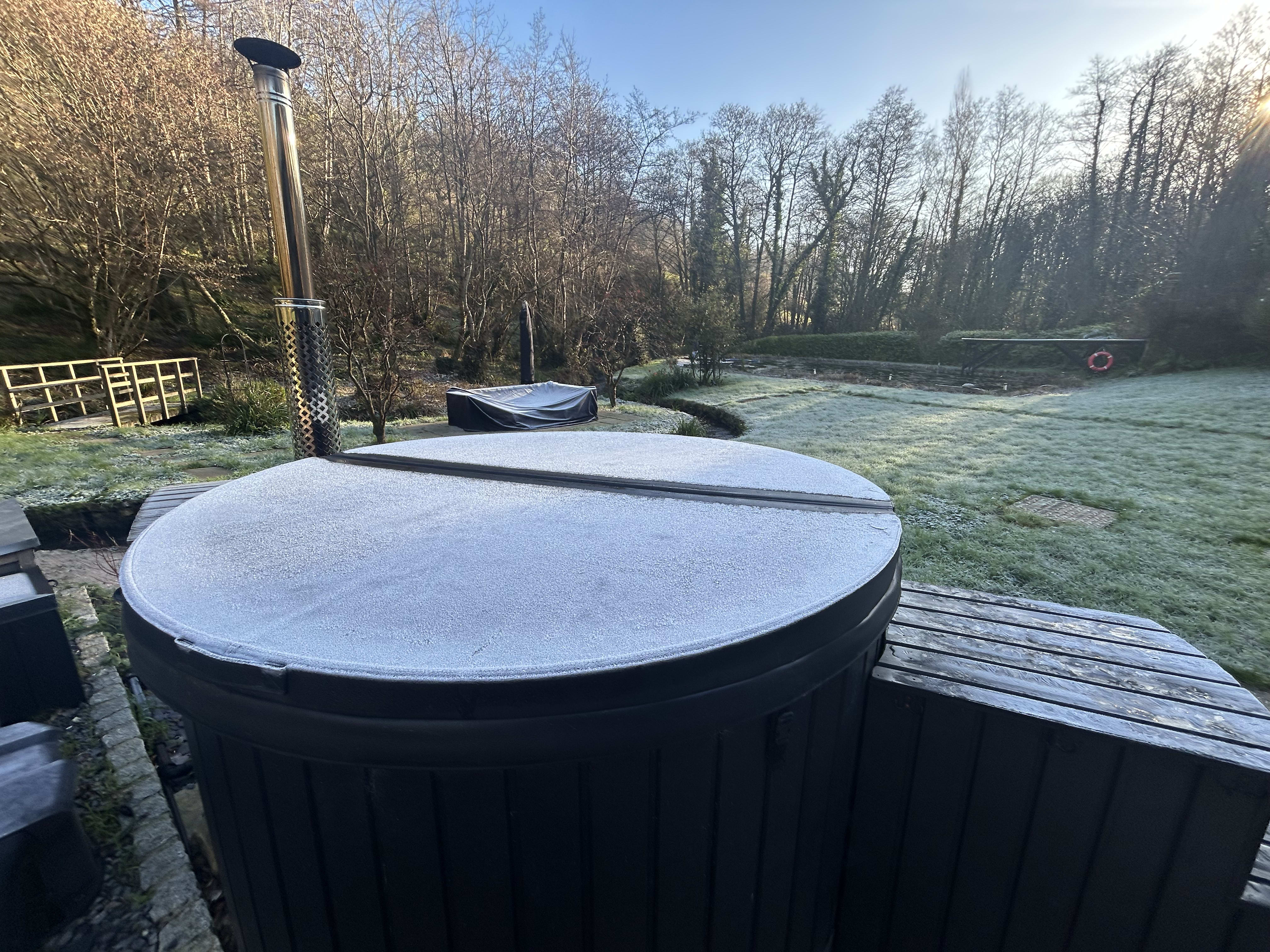 Soaking in the wood-fired hot tub at dusk at Hole Mill holiday cottage, Devon