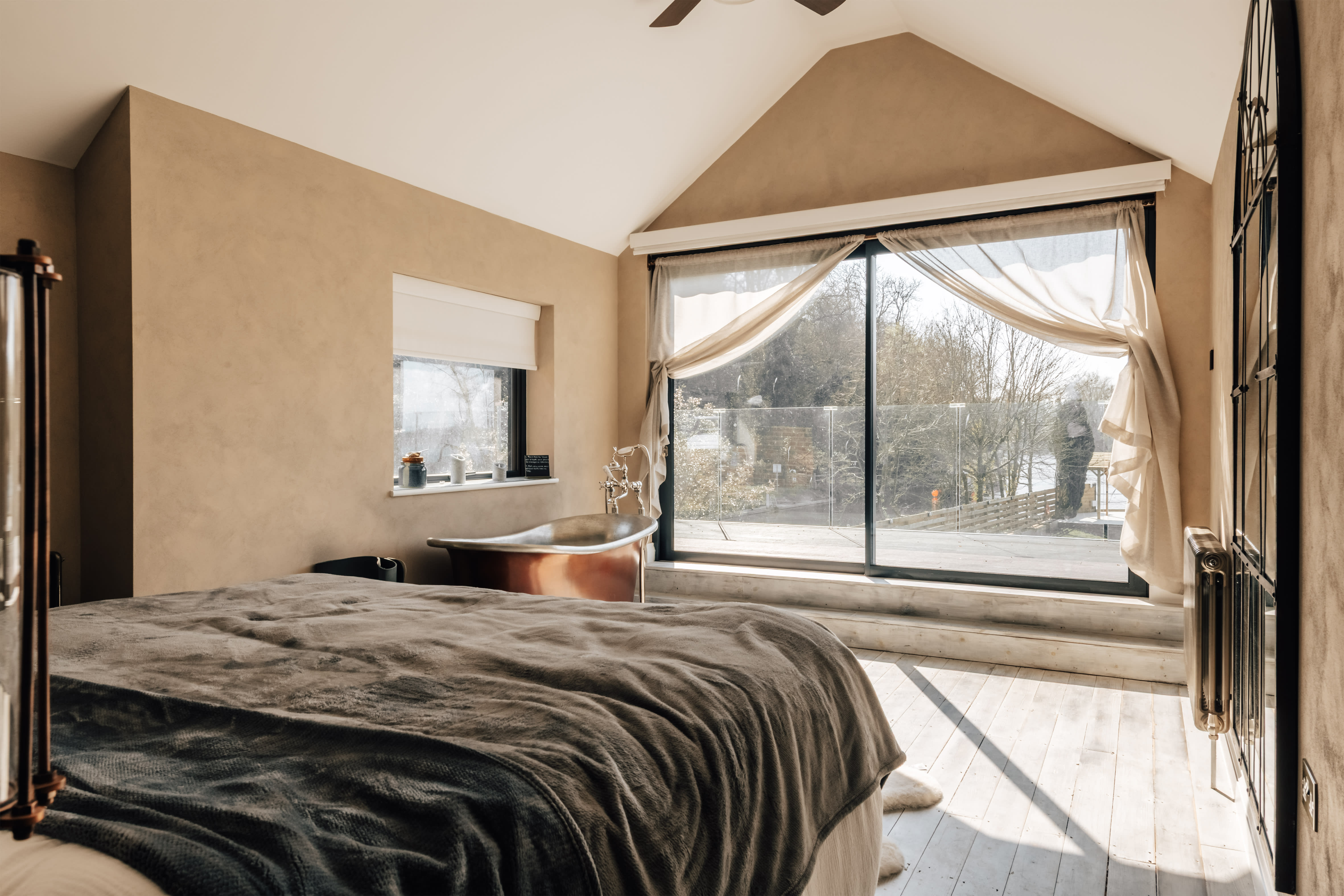 Master bedroom with a Super King bed, balcony and copper freestanding bath at Weir House, Sonning