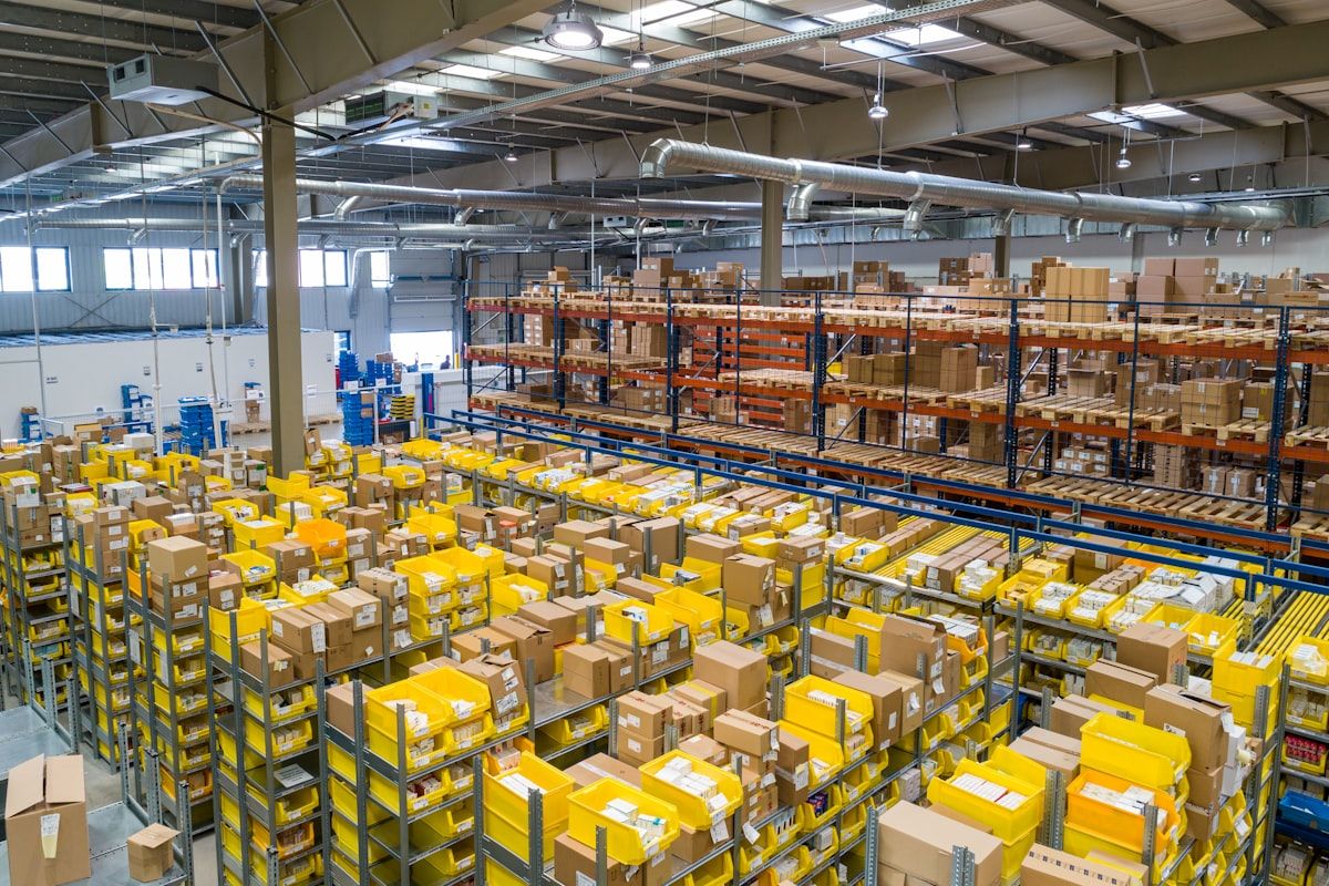 Warehouse worker reviewing purchase order documents on a tablet alongside shipping pallets