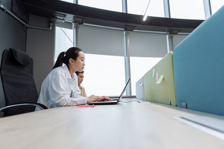 Two professionals working on laptops in a modern office setting with natural light