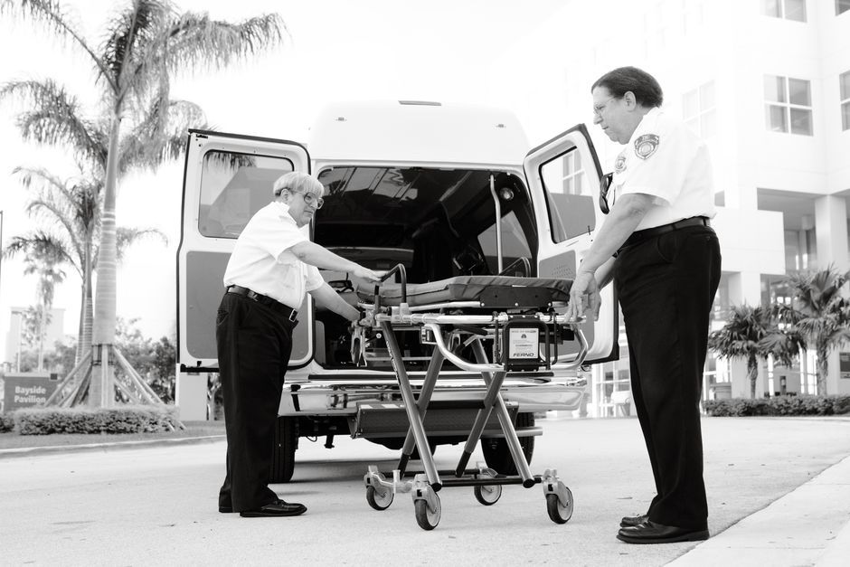Two paramedics organize a stretcher outside an ambulance, ready for an emergency call.