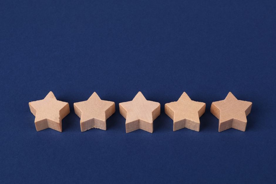 Five wooden stars on a blue background representing a rating system or evaluation concept.