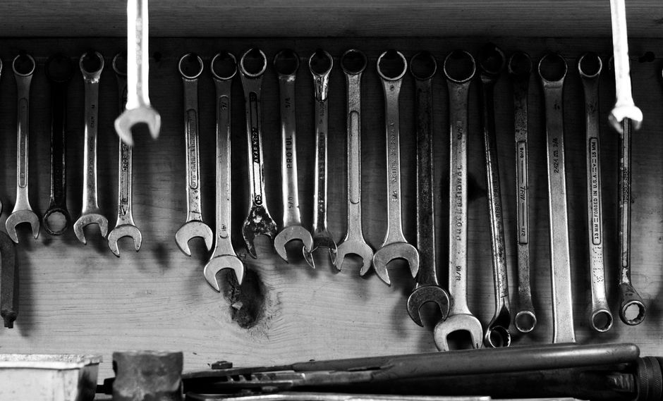 A black and white image of wrenches neatly hanging on a workshop wall.