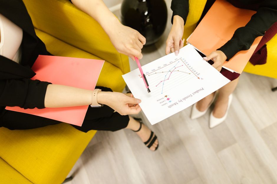 Two businesswomen in a meeting analyzing charts and graphs in an office setting.