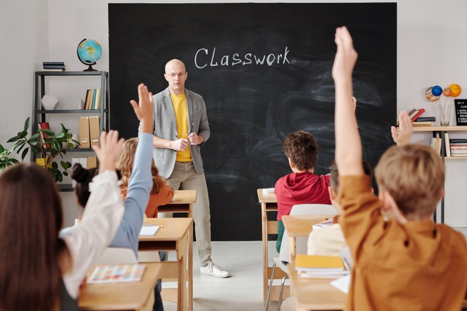 A teacher interacts with diverse students in a classroom, engaging them in active learning.