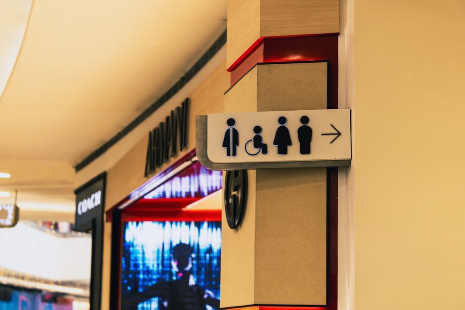 A restroom sign inside a shopping mall guiding to men's, women's, and accessible bathrooms.