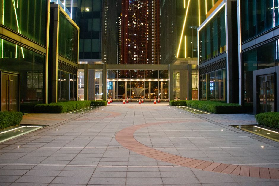 Vivid night view of modern city buildings with illuminated architecture and a paved walkway.