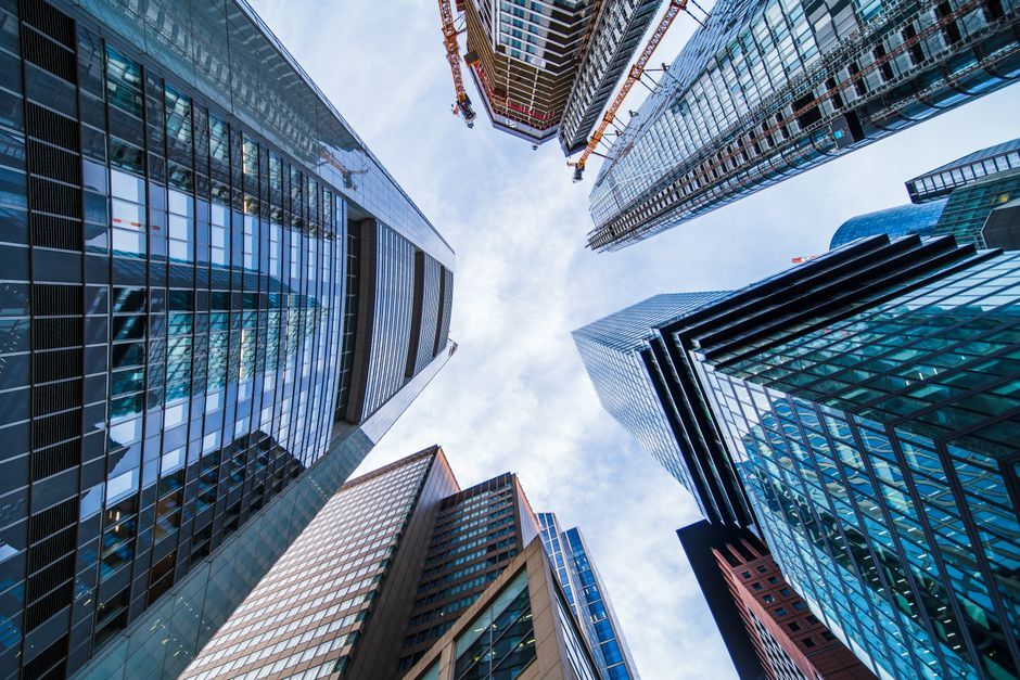 Modern skyscrapers with reflective glass facades stretching into a bright blue sky.